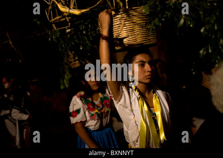 Young women dressed with traditional regional clothing carry baskets in their heads during holy week celebration, Oaxaca, Mexico Stock Photo