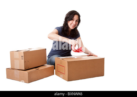 Attractive happy beautiful woman putting tape on cardboard moving storage boxes parcels preparing for mail, isolated. Stock Photo