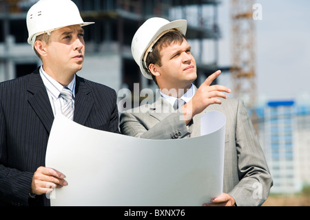Portrait of successful workers holding a project and discussing a building place Stock Photo