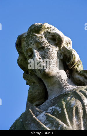 Weathered stone Graveyard Monument of an angel against vivid blue sky. Stock Photo