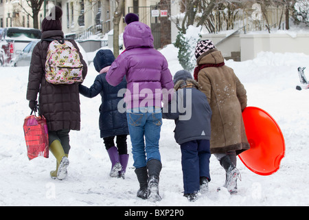 A  group on their way to go sledding in Riverside Park the day after a late December blizzard dumped more than two feet of snow Stock Photo