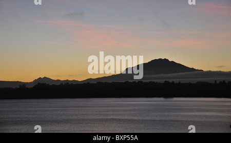 Pink clouds above the dawn silhouette of Volcan Calbuco, seen from Puerto Varas across the grey waters of Lake Llanquihue, Chile Stock Photo