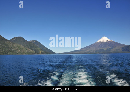 Blue sky waters of Todos los Santos lake, from the stern of a boat, towards the snow-capped cone of the Osorno Volcano, Chile Stock Photo