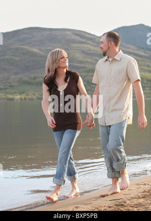 young Caucasian couple walking on mountain beach together Stock Photo