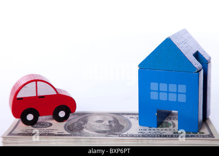 red car and blue house over a lot of dollar bills isolated on white (selective focus) Stock Photo