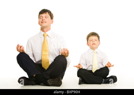 Photo of father and son sitting in pose of lotus with their eyes closed and meditating Stock Photo