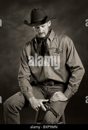 monochrome sepia portrait of cowboy holding pistol revolver Stock Photo