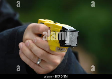 A taser electric charge stun gun being held in a policeman's hand and aimed Stock Photo