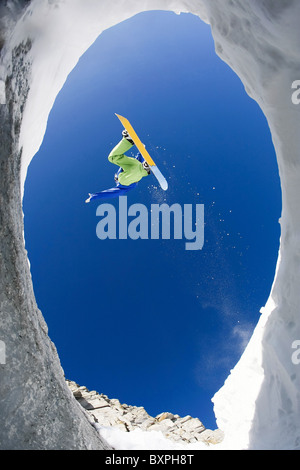 View from below of excited snowboarder leaping over mountainside and taking pleasure in it Stock Photo