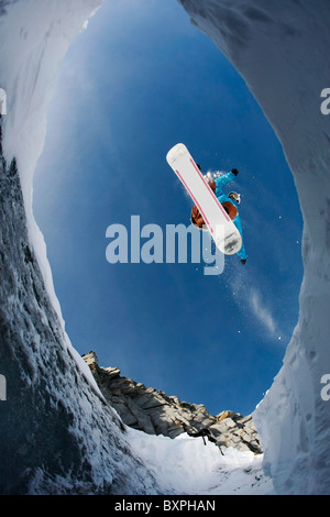 View from below of agile snowboarder in high jump over blue sky Stock Photo
