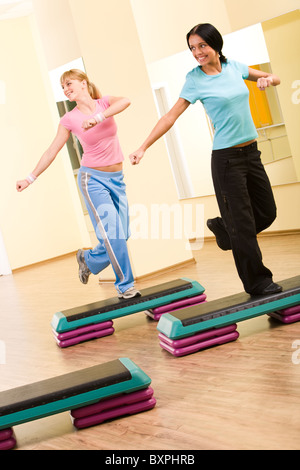 Two sporty women practicing physical exercises standing on one leg and looking to the right Stock Photo