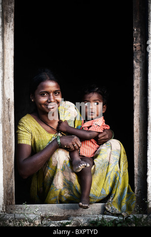 Happy smiling indian woman and her baby boy sat in their doorway. Andhra Pradesh, India. Stock Photo