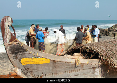 Fishermen work on their net beside the Arabian Sea in Kerala, India. T Stock Photo