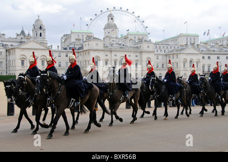 A column of Household Cavalry marching past horse guards parade with the Horse Guard building and London Eye in the background Stock Photo