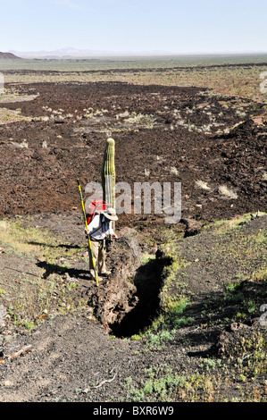 Geologist viewing small lava tube on side of Tecolote cinder cone, El Pinacate Biosphere Reserve, Sonora, Mexico Stock Photo