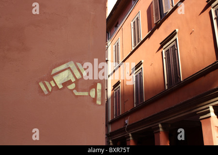 Spray painted CCTV camera on a red wall on an Italian street Stock Photo