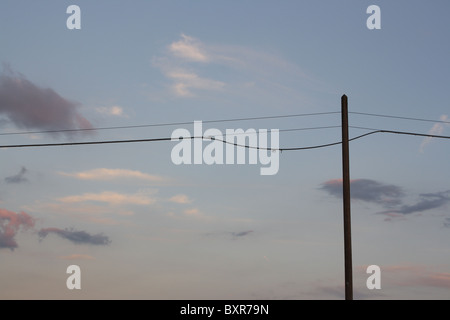 Silhouette of a telegraph pole at dusk against a blue sky Stock Photo