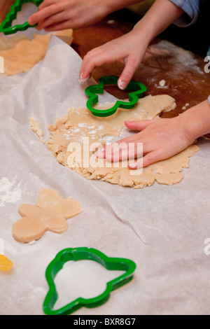 Child's hands cutting out sugar cookie dough at the kitchen table Stock Photo