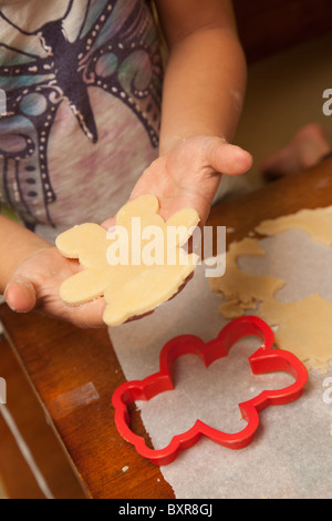 Child's hands cutting out sugar cookie dough at the kitchen table Stock Photo