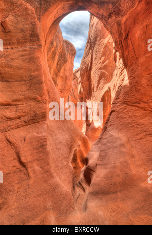Surreal HDR image of arches and holes in the eroded, narrow, red sandstone confines of Peekaboo Canyon Stock Photo