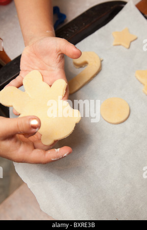 Child's hands cutting out sugar cookie dough at the kitchen table Stock Photo