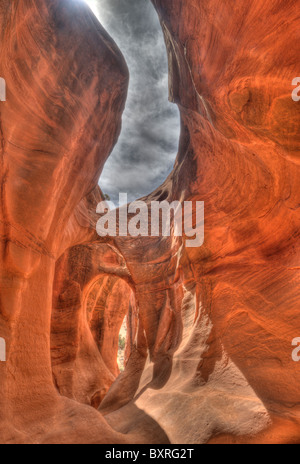 Surreal HDR image of arches and holes in the eroded, narrow, red sandstone confines of Peekaboo Canyon Stock Photo