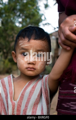 A young Burmese boy whose family fled war atrocities in Burma is holding his mother's hand in Ban Tha Ta Fang, Thailand.. Stock Photo