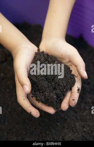 Child's hands holding pile of soil