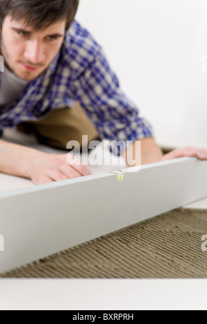 Home tile improvement - handyman with level laying down tile floor Stock Photo