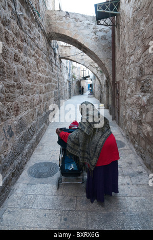 Ethiopian woman with veil pushing a trolley with toddler in Christian Quarter. jerusalem Old City Stock Photo
