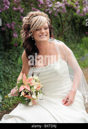 pretty Caucasian bride sitting outdoors and laughing Stock Photo
