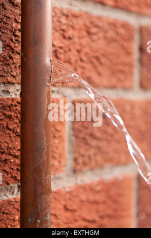 Water coming out of a burst copper water pipe which had been broken by freezing ice. Stock Photo