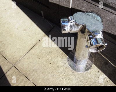 Shiny new silver fire hydrant on a city sidewalk. Stock Photo