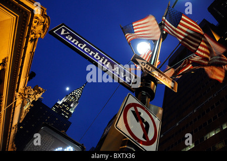 Chrysler building in twilight framed with street sign for Vanderbilt Ave and American flags; New York City, USA Stock Photo