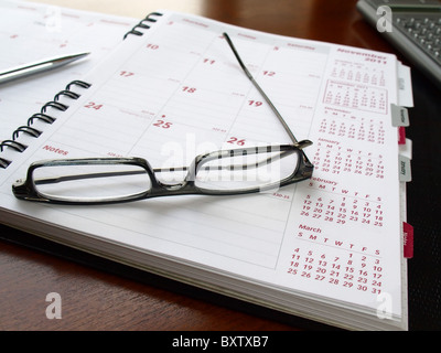 Monthly planner with reading glasses and pen on the table Stock Photo