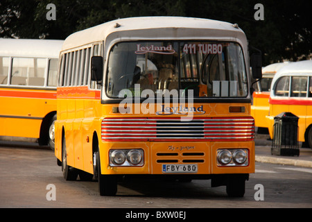 An empty yellow bus is parked in a lot on the side of a street. Stock Photo