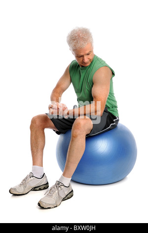 Mature mas exercising seated on fitness ball isolated over white background Stock Photo