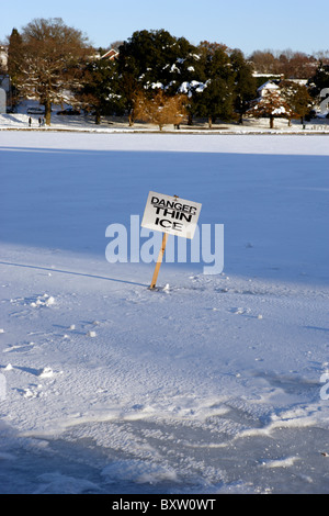 'Danger Thin ice' sign stuck in the ice on a lake Stock Photo