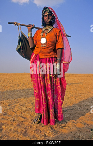 Woman in festival dress carrying baby in sling, Pushkar Fair, Rajasthan, India Stock Photo