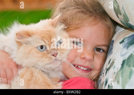 Pre-school girl 3 4 5 year years old holding Orange Tabby Persian domesticated domestic cat in backyard eye contact POV MR © Myrleen Pearson