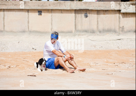 Middle aged man sits on beach with pet English Springer Spaniel dog at Beverly Beach, Florida Stock Photo