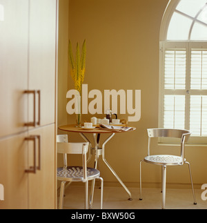 Small circular metal table and metal chairs in dining corner of modern kitchen Stock Photo