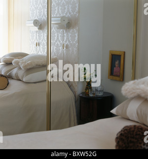 Mirrored doors on fitted wardrobe in small townhouse bedroom Stock Photo