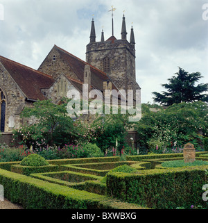 Clipped box hedges in formal knot garden in walled garden below country church Stock Photo