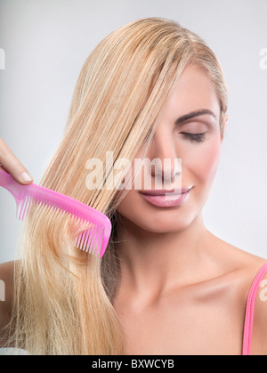 Young woman combing hair Stock Photo