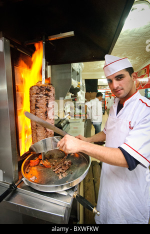 ISTANBUL, Turkey / Türkiye — A cook carving slices of a grilling doner kebap in Istanbul, Turkey. Stock Photo