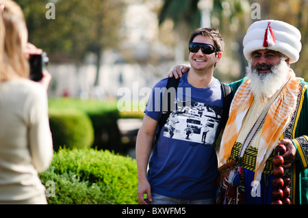 ISTANBUL, Turkey / Türkiye — Tourists pose for a photo with a street performer dressed in the costume of an Ottoman sultan near the Blue Mosque in Istanbul, Turkey. Stock Photo