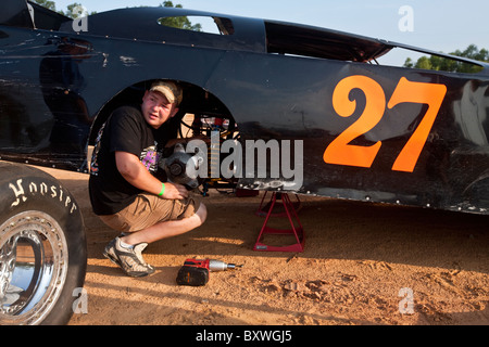 USA, Mississippi, Gulfport, Young man working in wheel well of stock car in pits at South Mississippi Speedway Stock Photo