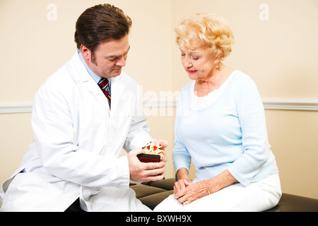 Chiropractor uses a model of the human spine to explain treatment to a patient.  Stock Photo