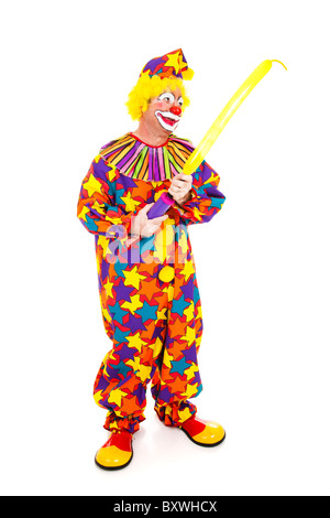 Clown blows up a special balloon for making balloon animals. Full body isolated on white.  Stock Photo